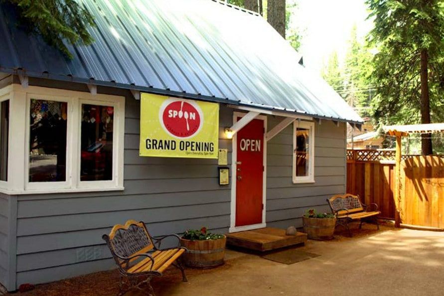 A small house with a yellow sign that says grand opening