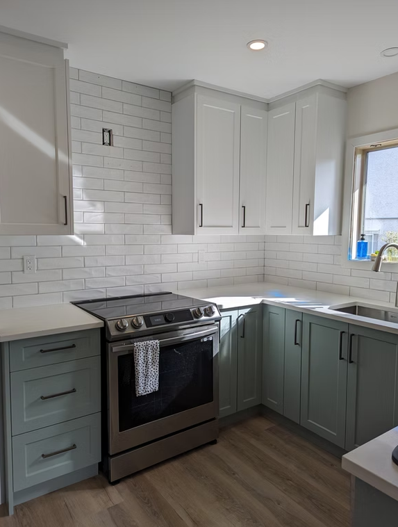 Modern kitchen with white subway tile, gray cabinets, black stove, and wood-look flooring.