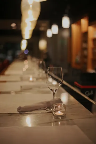 A wine glass and a candle are on a table in a restaurant.