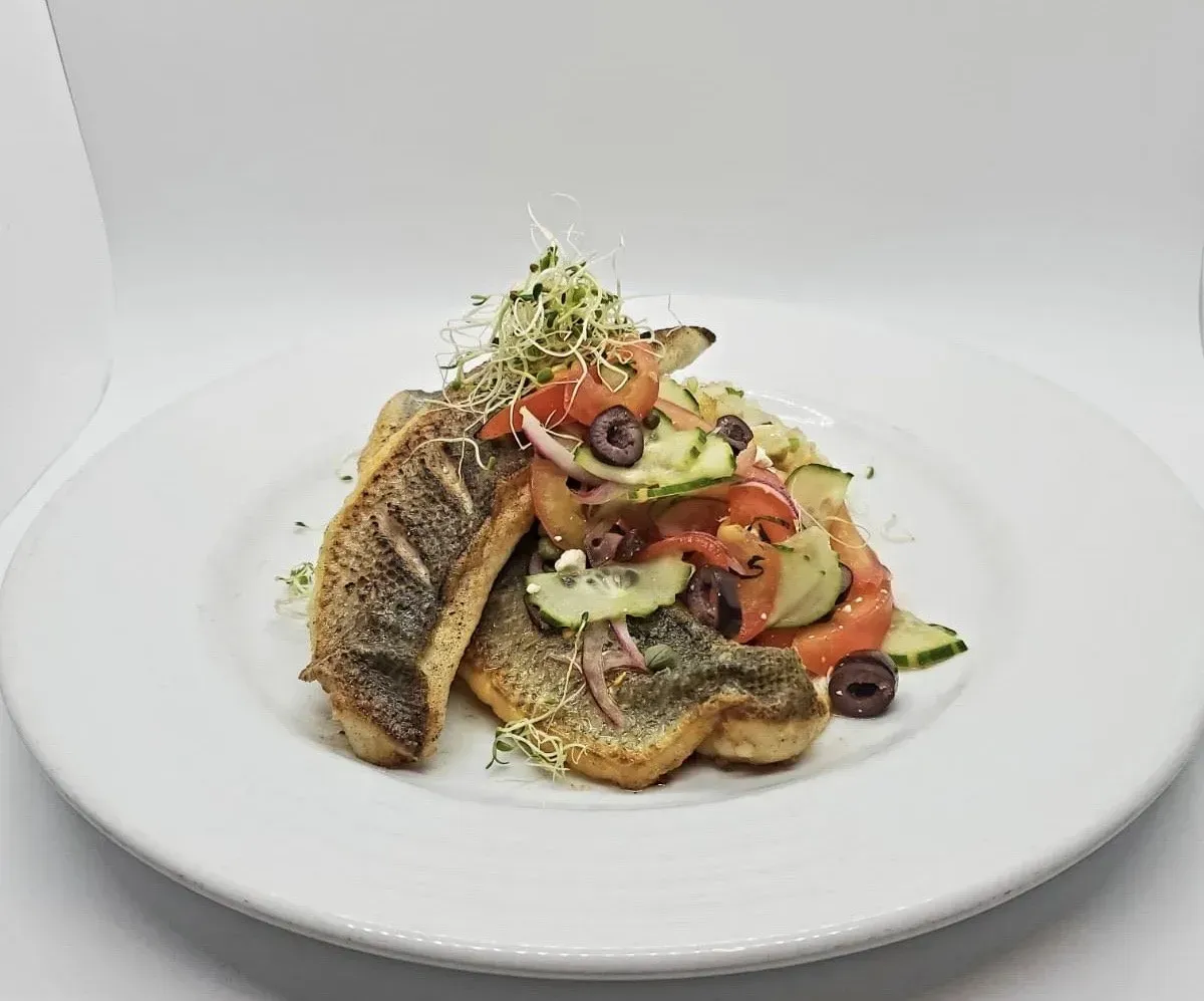 A white plate topped with a salad of fish and vegetables.
