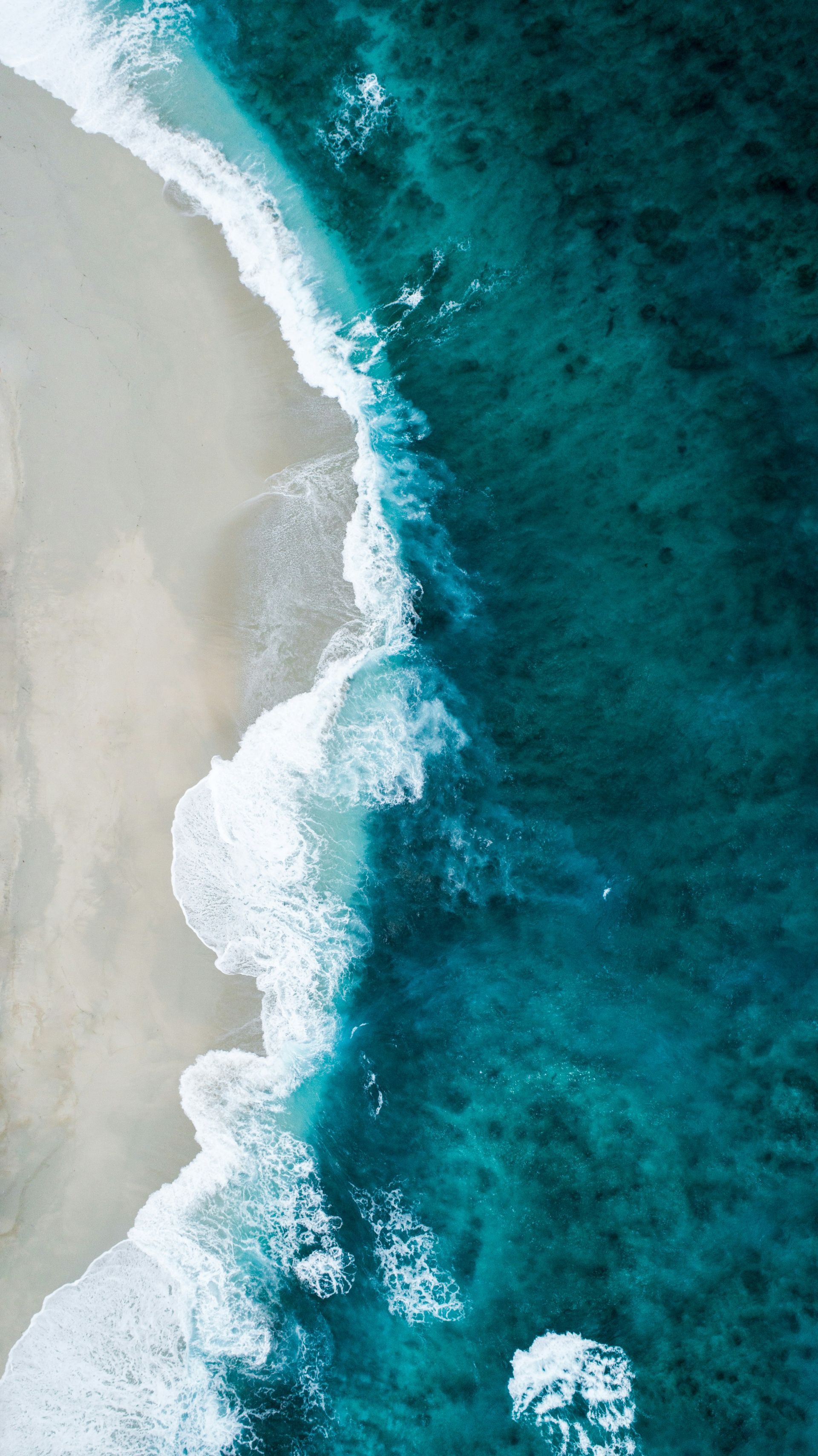 An aerial view of a beach with waves crashing on it.