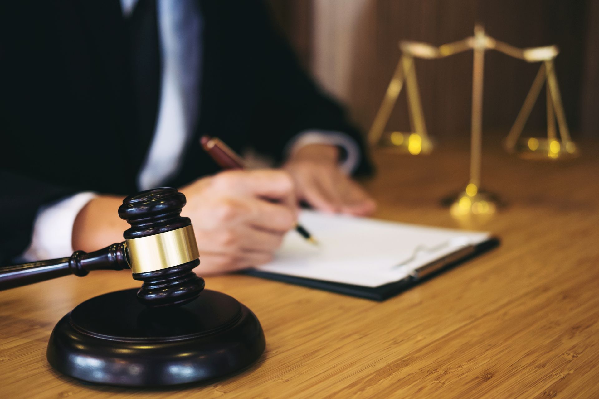 Gavel, legal paperwork, and scales of justice on wooden desk in a law office setting.