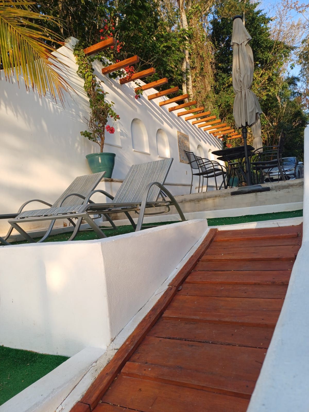 A wooden ramp leads to a patio with chairs and umbrellas