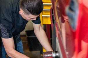Mechanic working on a red vehicle wheel, in a garage | Allegiance Automotive