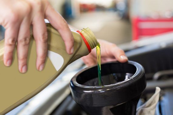 Person pouring motor oil from a container into a funnel in an engine bay | Allegiance Automotive