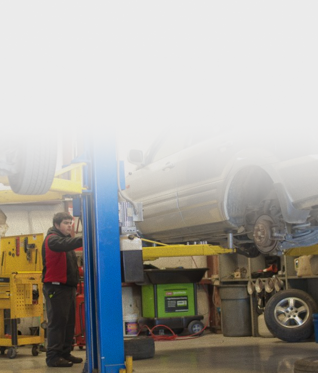 Mechanic working on a car lifted on a hoist in a repair shop | Allegiance Automotive