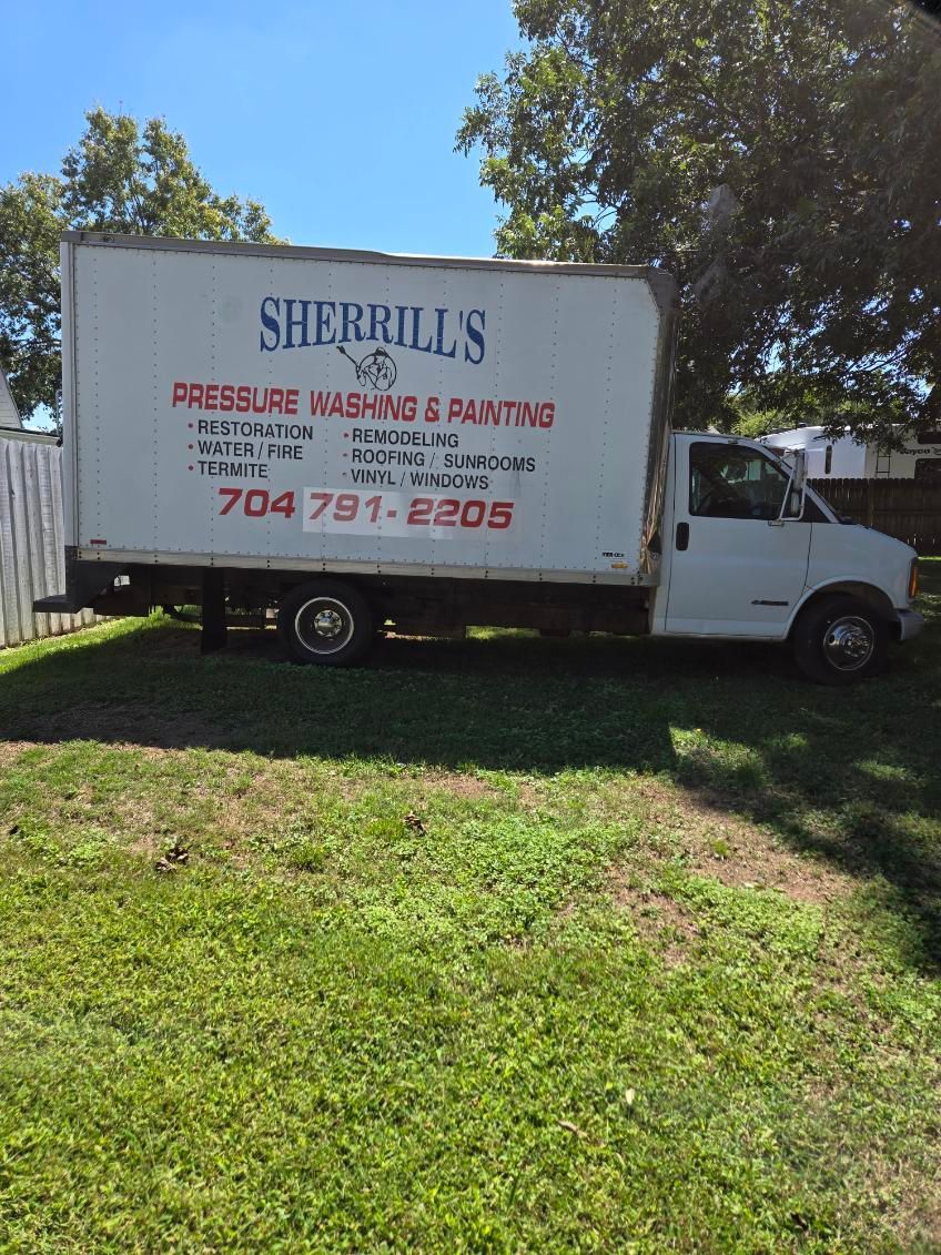 A man wearing a red hard hat is standing on a roof.