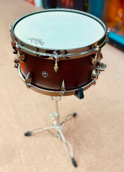 A snare drum is sitting on a stand on the floor