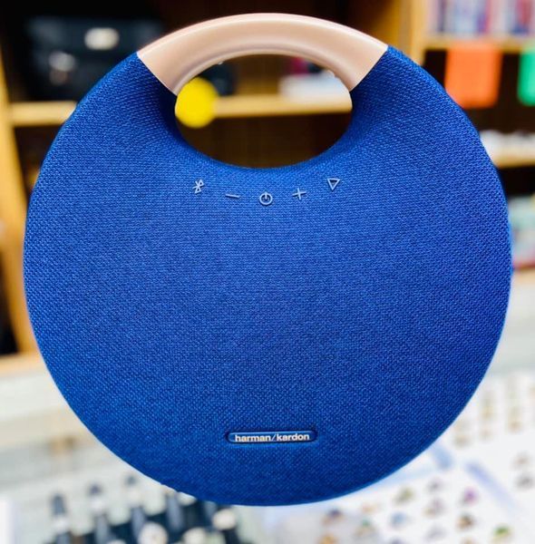 A blue harman kardon speaker is sitting on a table