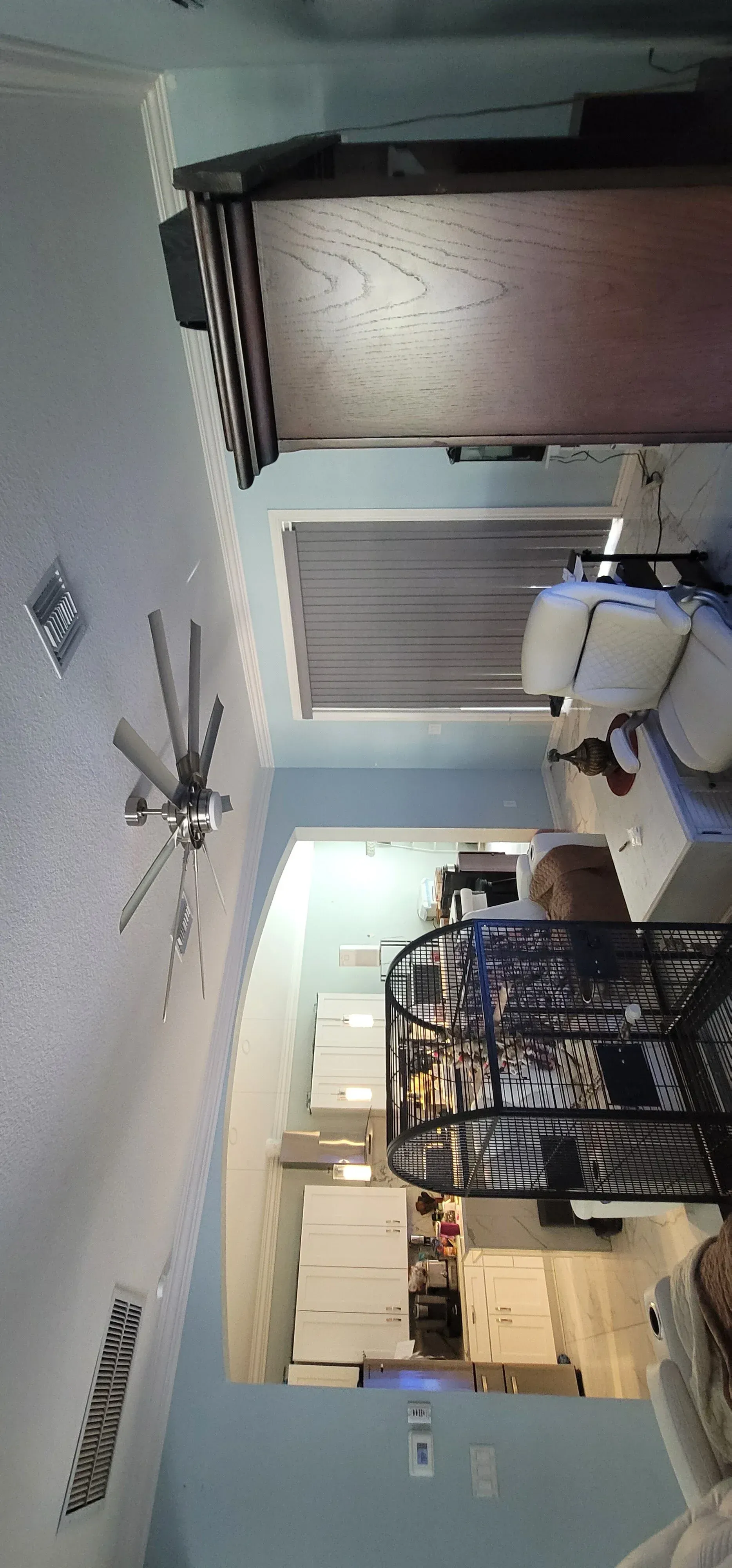 A room interior with a ceiling fan, cabinets, and furniture.