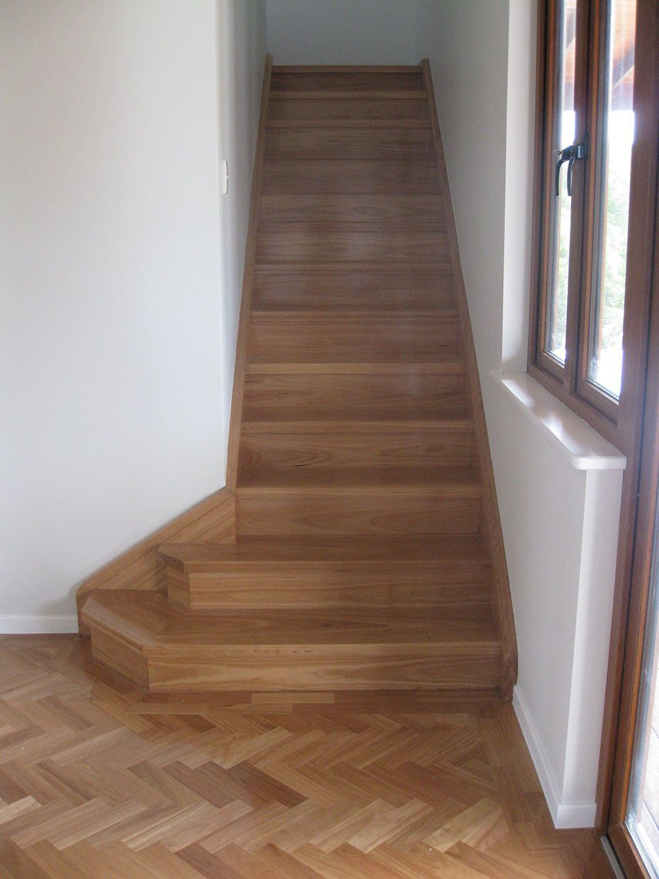 A Wooden Staircase in a Hallway With a Window — Sven Margraf Constructions Pty Ltd In Atherton QLD