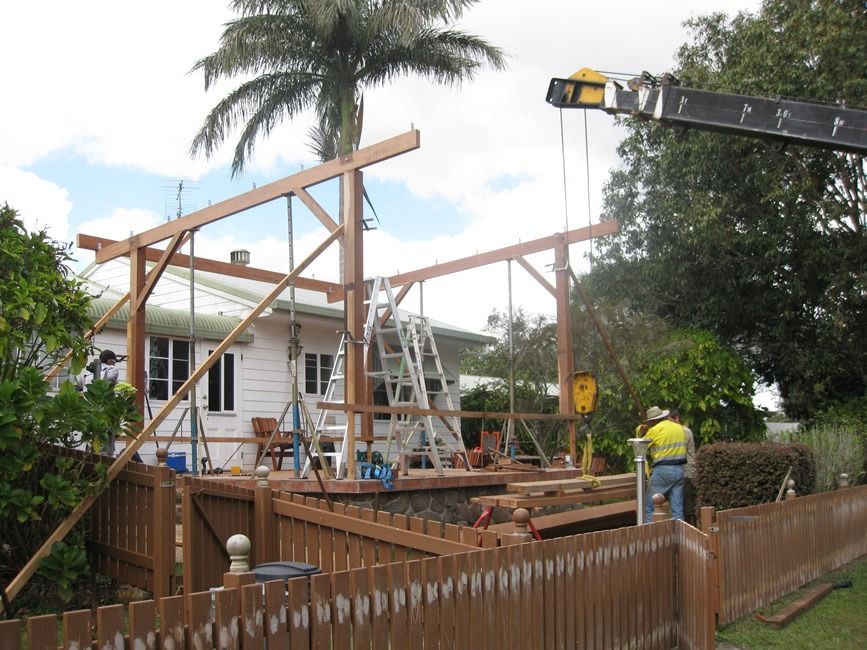 A Crane Is Lifting A Wooden Structure In Front Of A House — Sven Margraf Constructions Pty Ltd In Atherton QLD