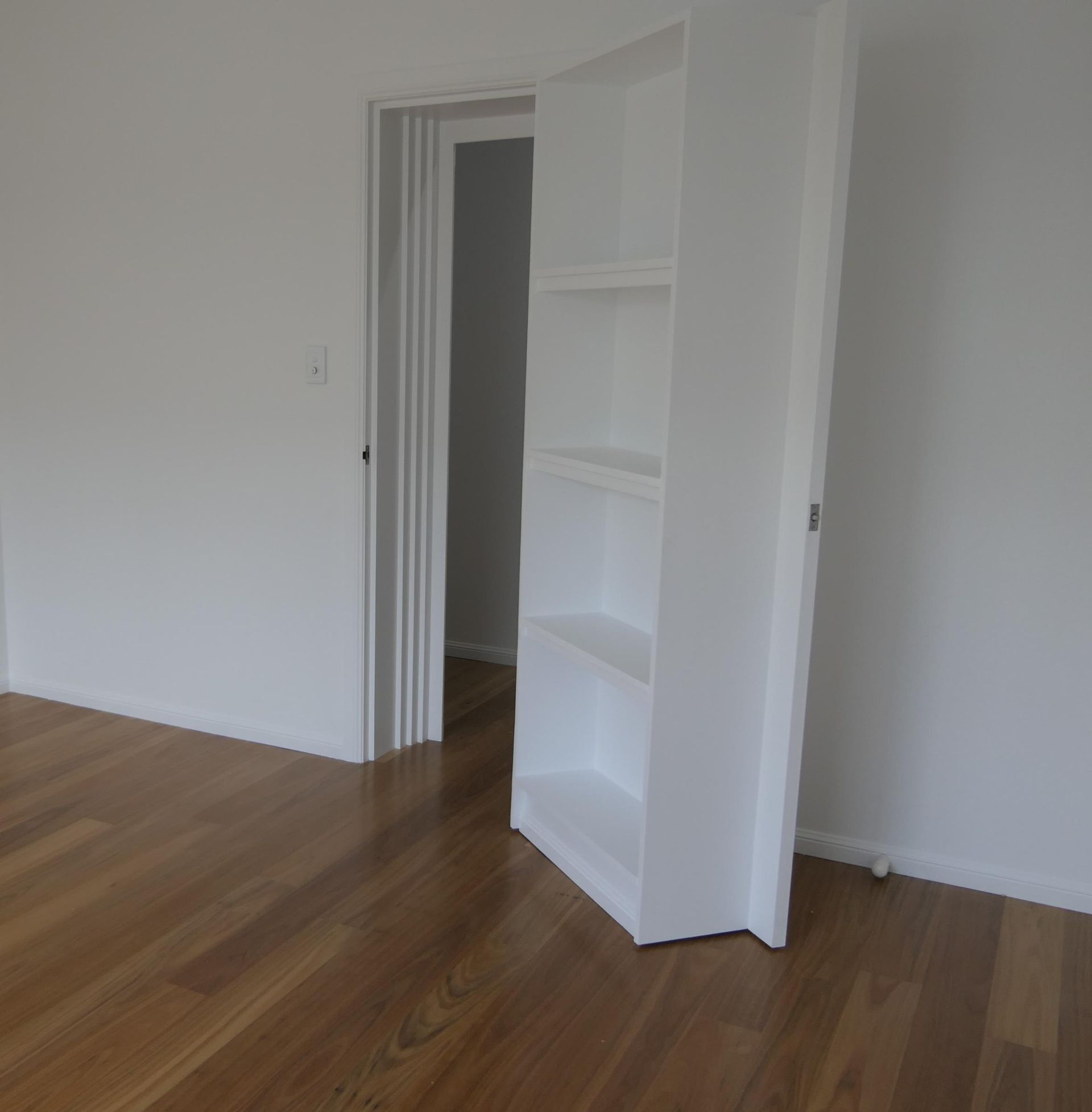 An Empty Room With Hardwood Floors And A White Bookshelf — Sven Margraf Constructions Pty Ltd In Atherton QLD
