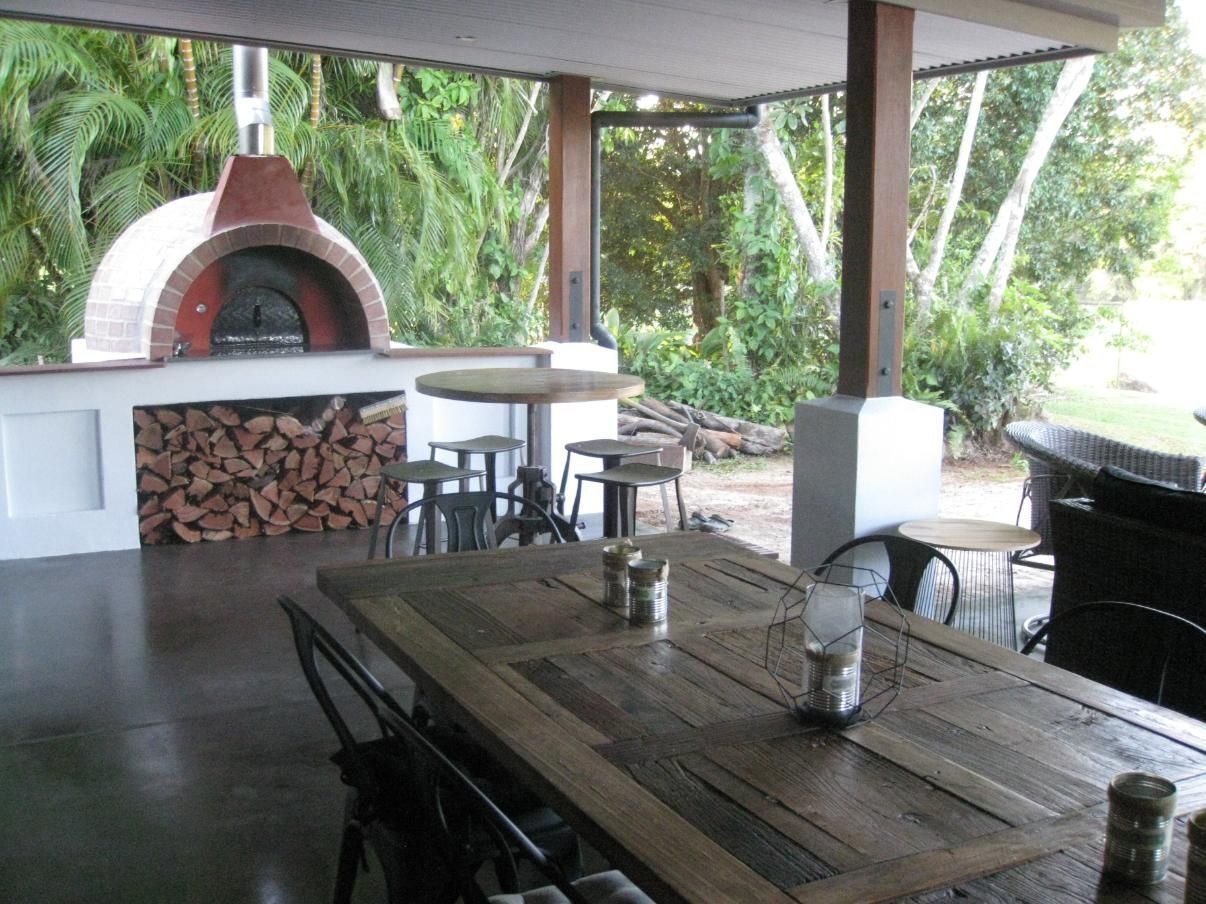 A Wooden Table With Candles On It In Front Of A Pizza Oven — Sven Margraf Constructions Pty Ltd In Atherton QLD