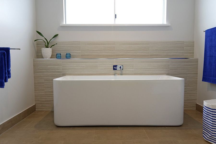 A Bathroom With A White Bathtub And Blue Towels — Sven Margraf Constructions Pty Ltd In Atherton QLD