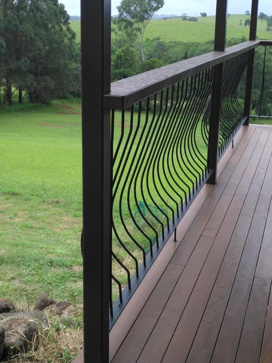 A Wooden Deck With A Wrought Iron Railing Overlooking A Grassy Field — Sven Margraf Constructions Pty Ltd In Atherton QLD