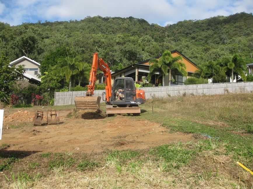 A Large Orange Excavator Is Sitting In The Middle Of A Dirt Field — Sven Margraf Constructions Pty Ltd In Atherton QLD