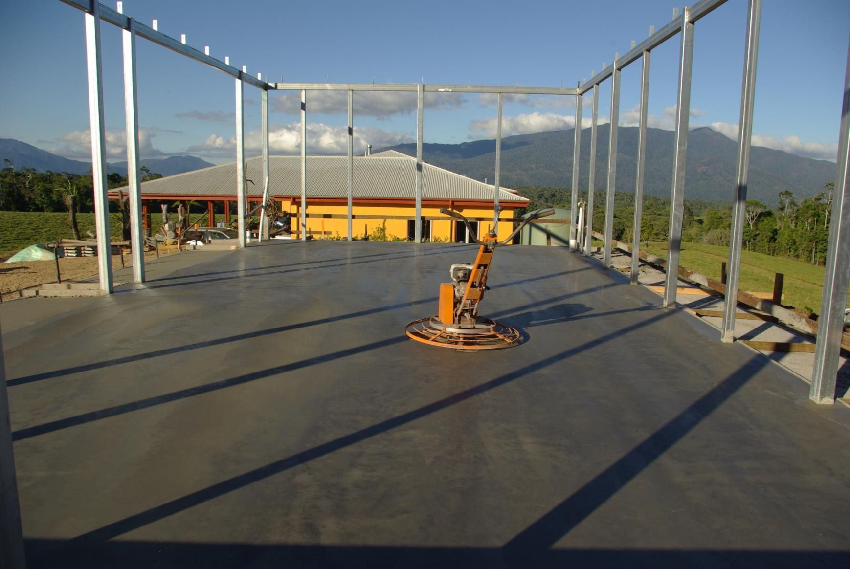 A Concrete Floor With A Machine On It In Front Of A House — Sven Margraf Constructions Pty Ltd In Atherton QLD