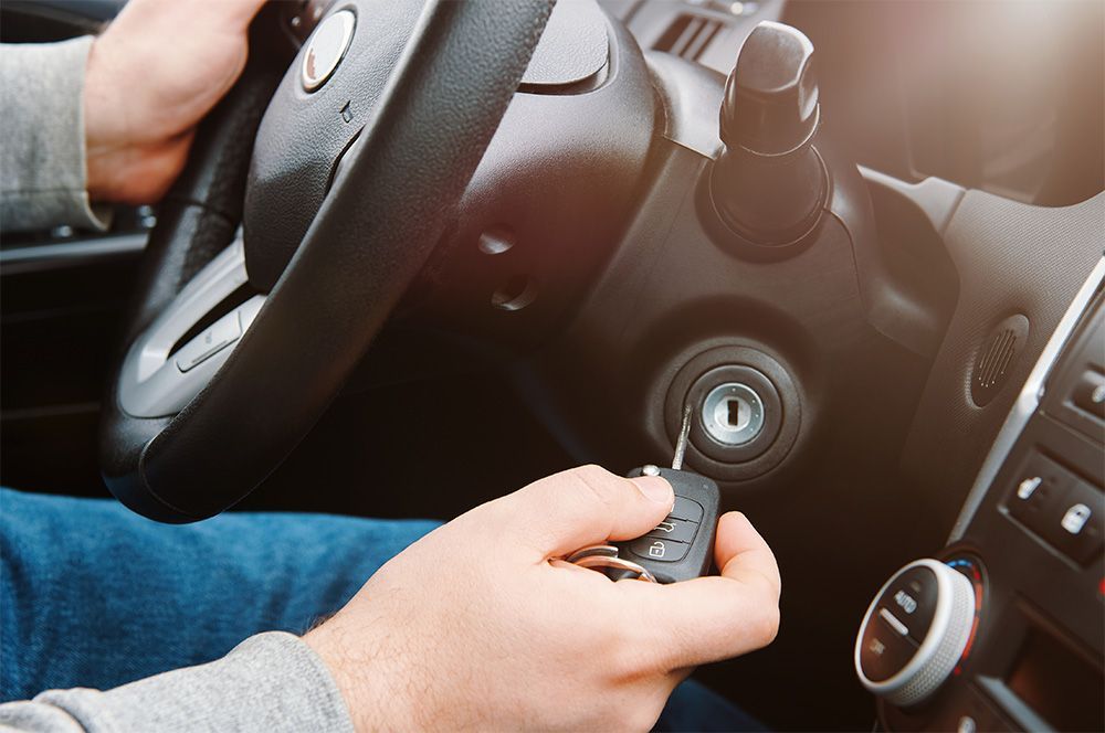 Un hombre sostiene una llave de coche en su mano mientras conduce un automóvil.