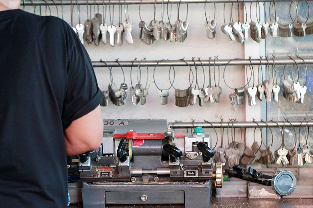 Un hombre está trabajando en una máquina de llaves en una cerrajería.