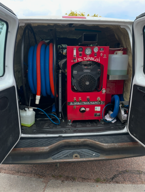 The back of a white van with a red machine in the back