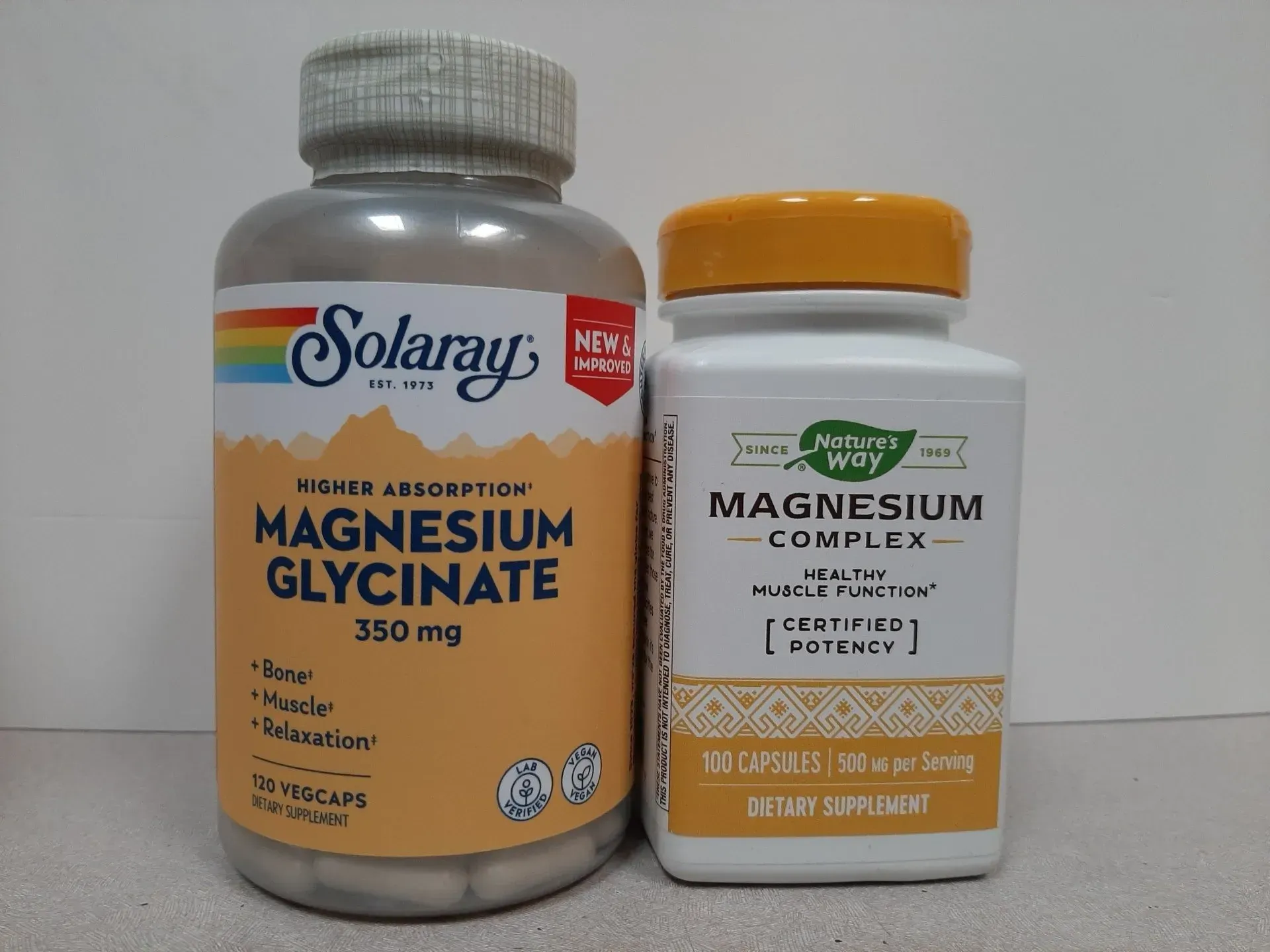 Two bottles of magnesium dietary supplements side by side on a plain surface.