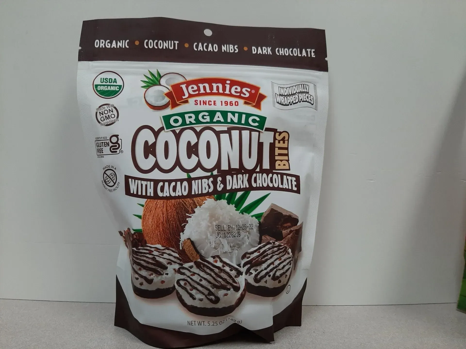A white bag of Jennies Organic Coconut Bites with cacao nibs and dark chocolate, featuring product photos on the front.