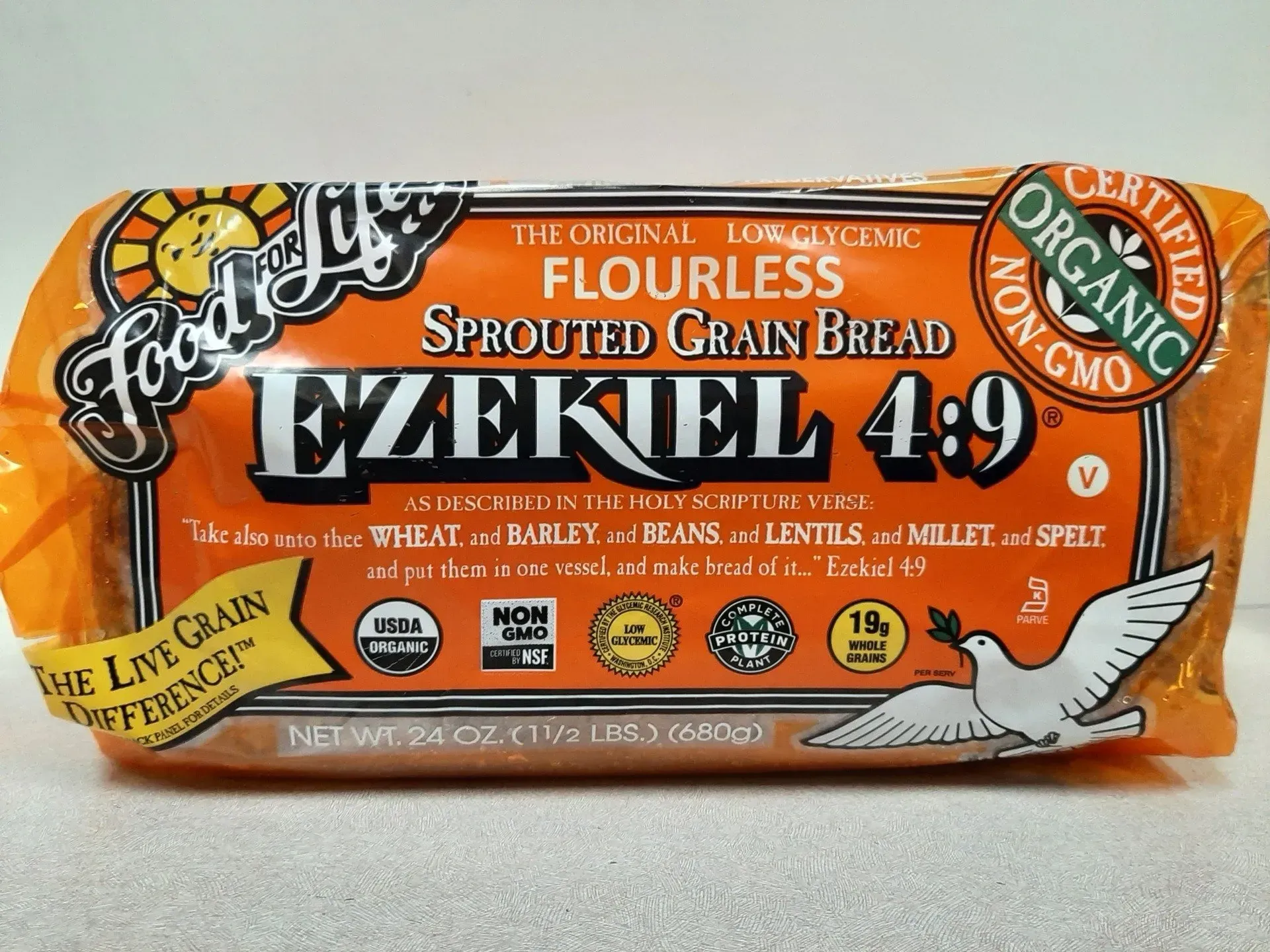 A loaf of Food for Life Ezekiel 4:9 sprouted grain bread in orange plastic packaging with a white dove illustration.