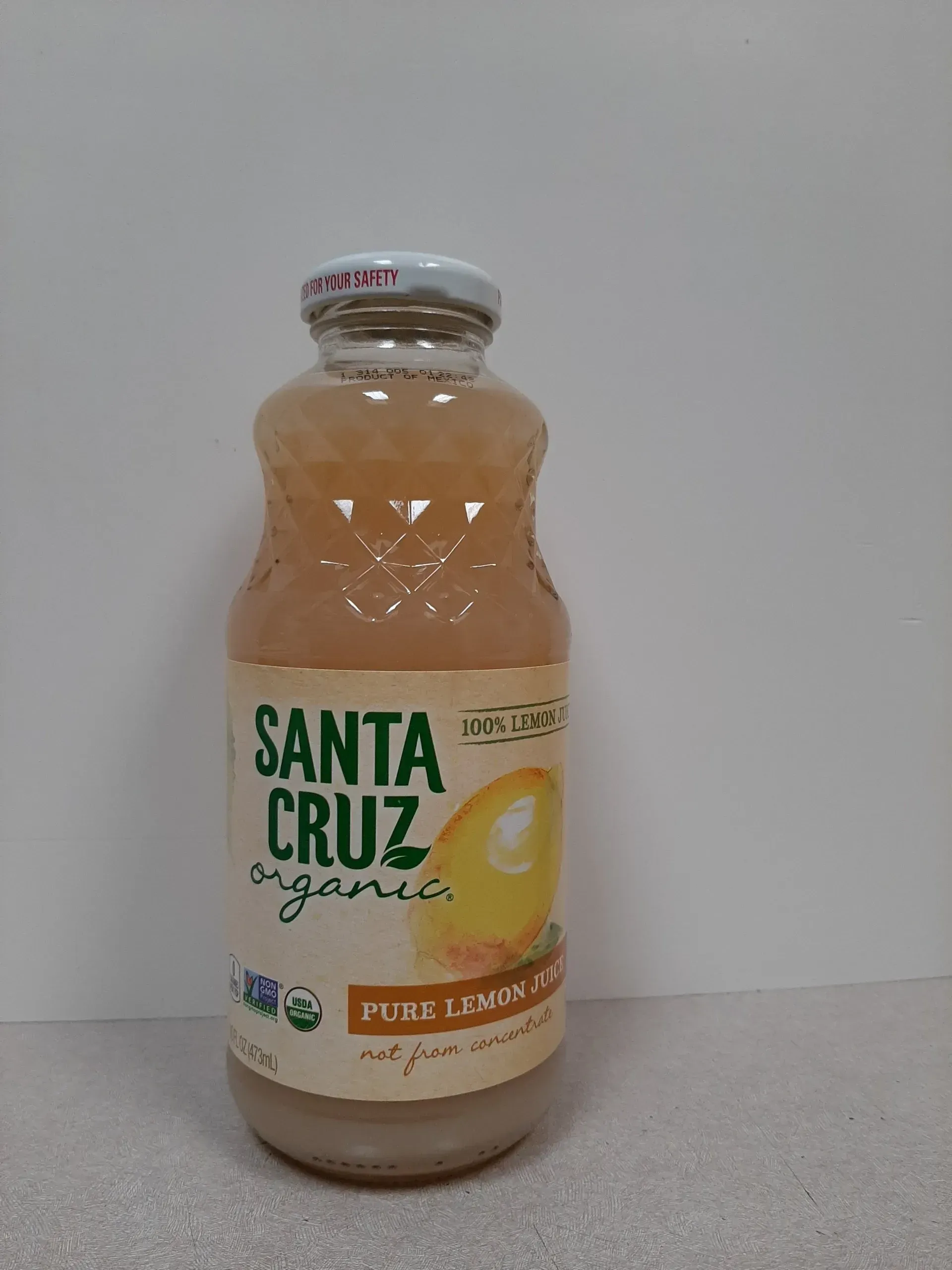 A bottle of Santa Cruz Organic pure lemon juice on a neutral background.