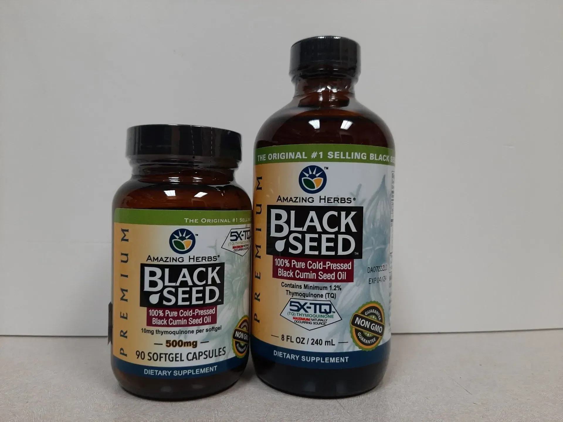 Two bottles of Amazing Herbs Premium Black Seed supplement, one containing softgel capsules and the other liquid oil.