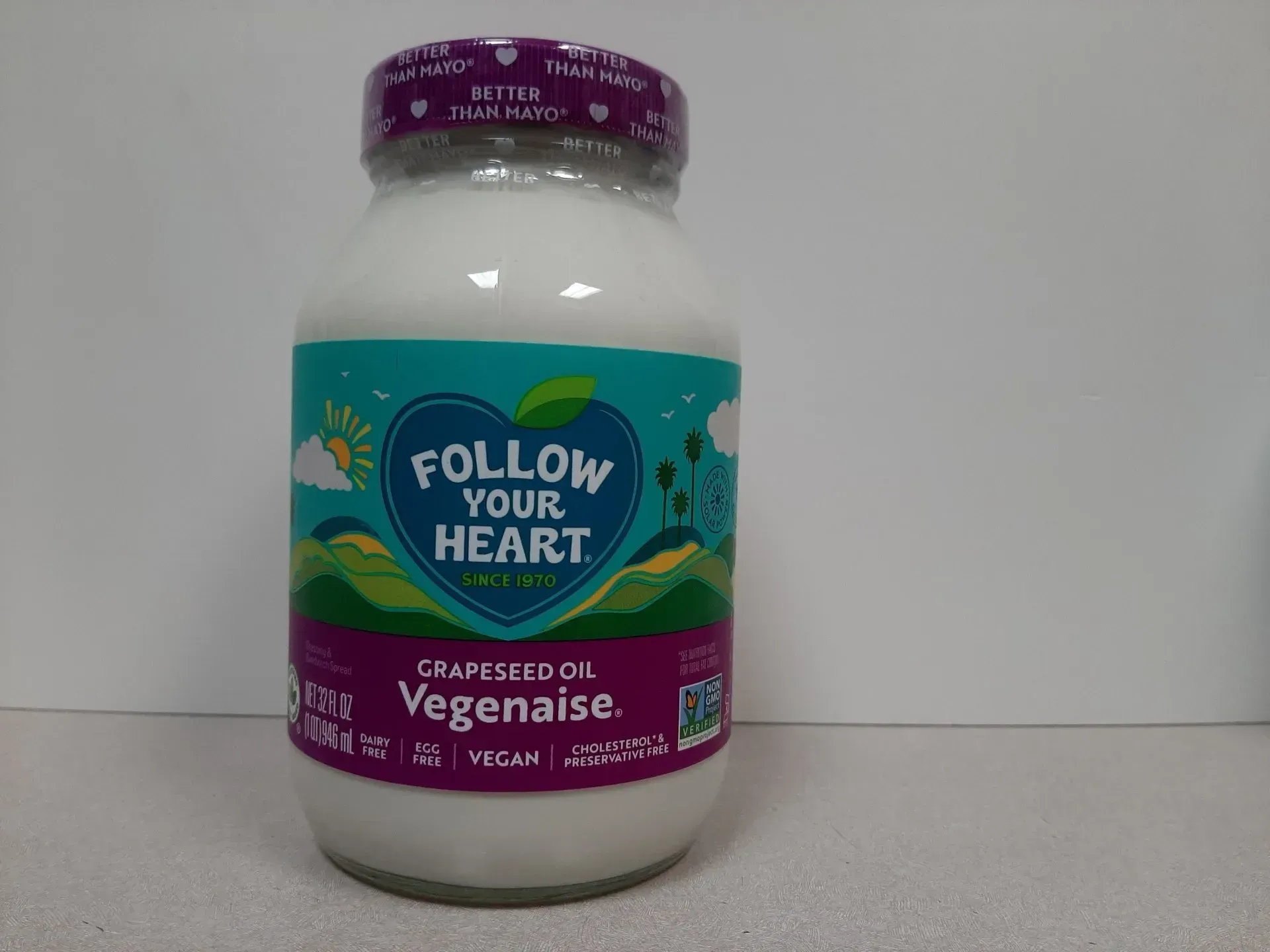 A jar of Follow Your Heart Grapeseed Oil Vegenaise with a white lid, positioned against a plain, light background.