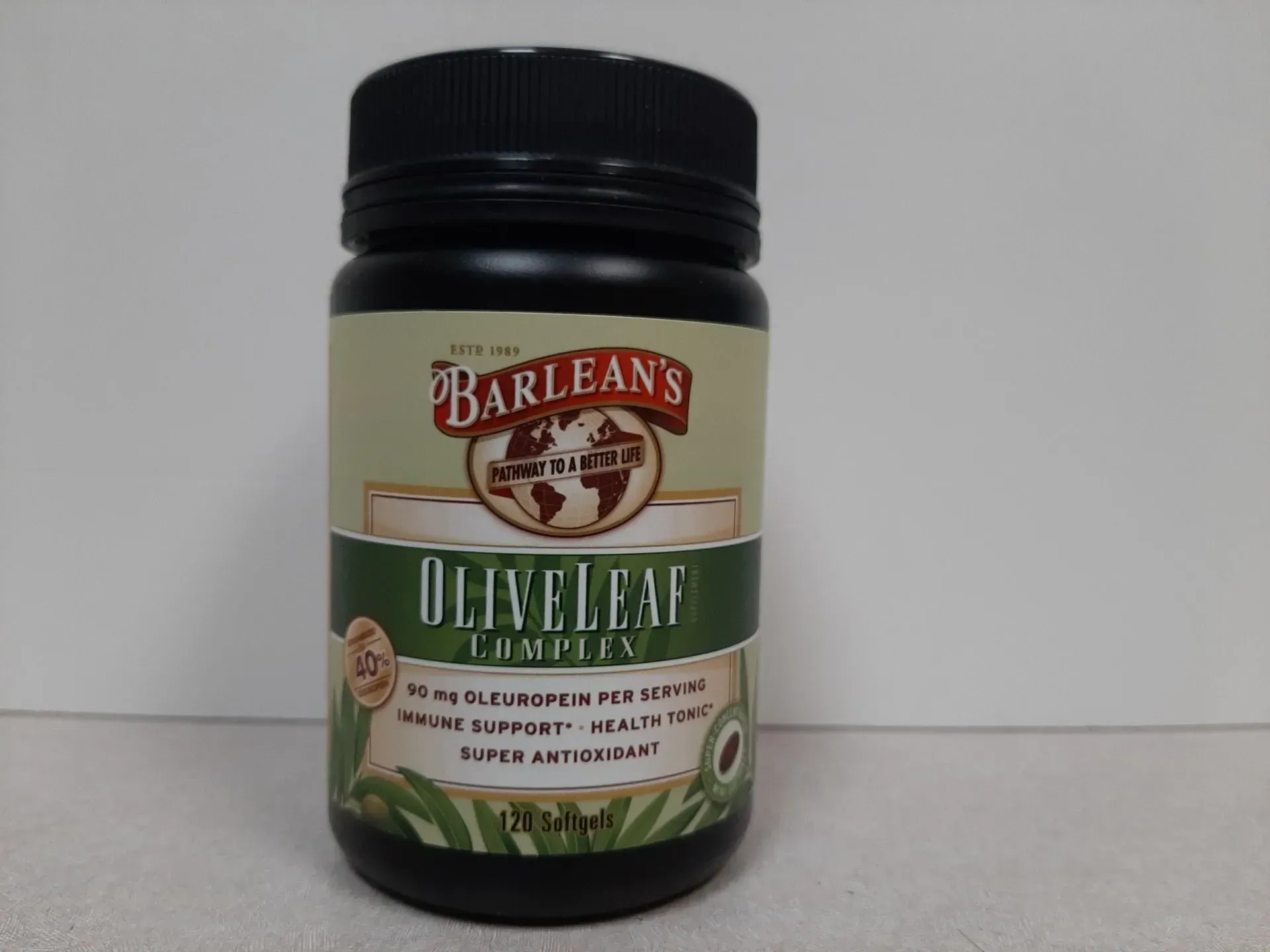 A black plastic bottle of Barlean's Olive Leaf Complex supplement with a tan label against a plain white background.