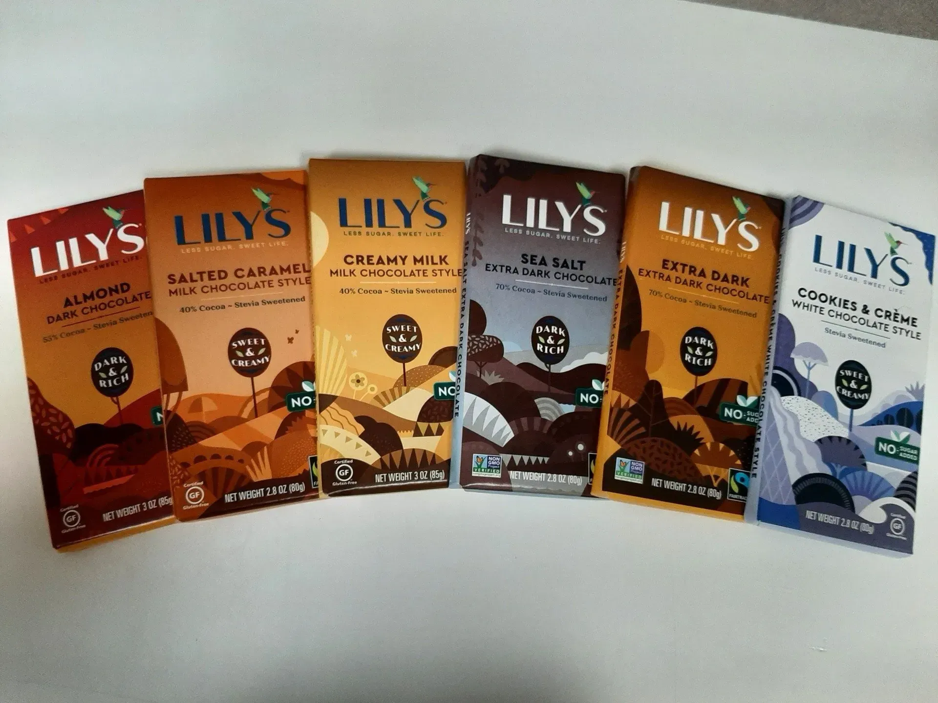 Six Lily's chocolate bars in various flavors lined up against a white background.