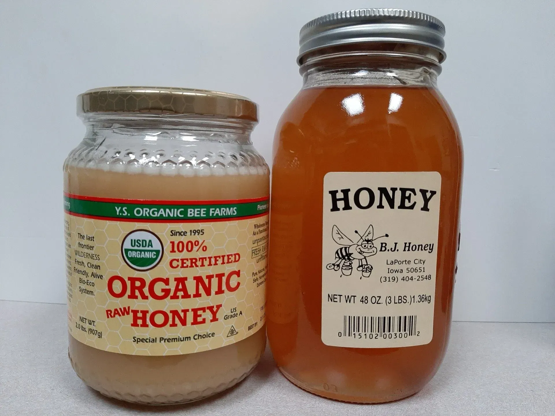 Two glass jars of honey sitting side-by-side.