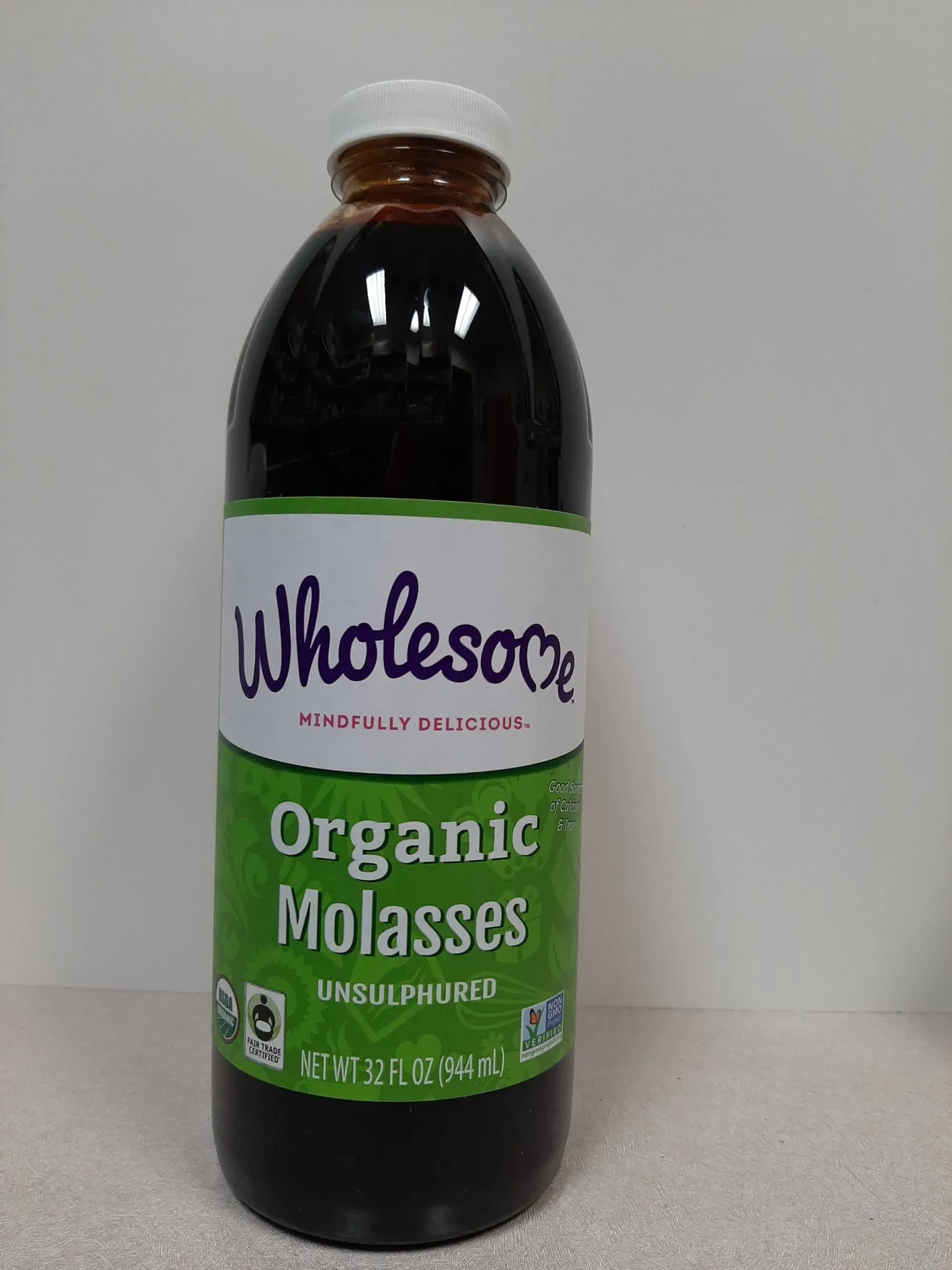 A bottle of Wholesome brand Organic Molasses with a green and white label on a light surface.
