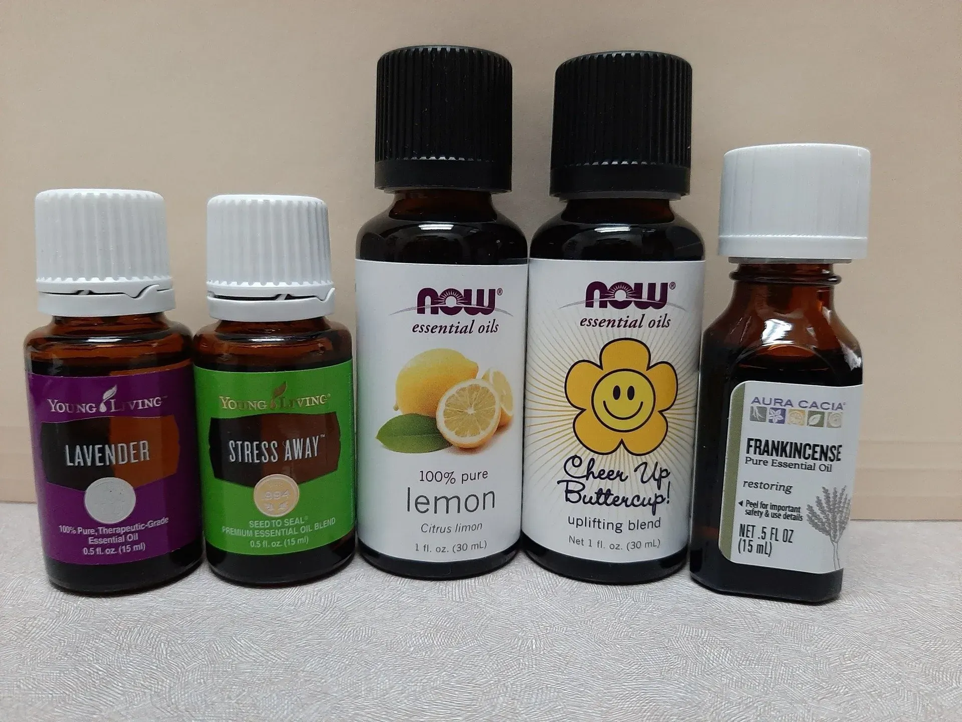 Five bottles of various essential oils lined up against a plain background.