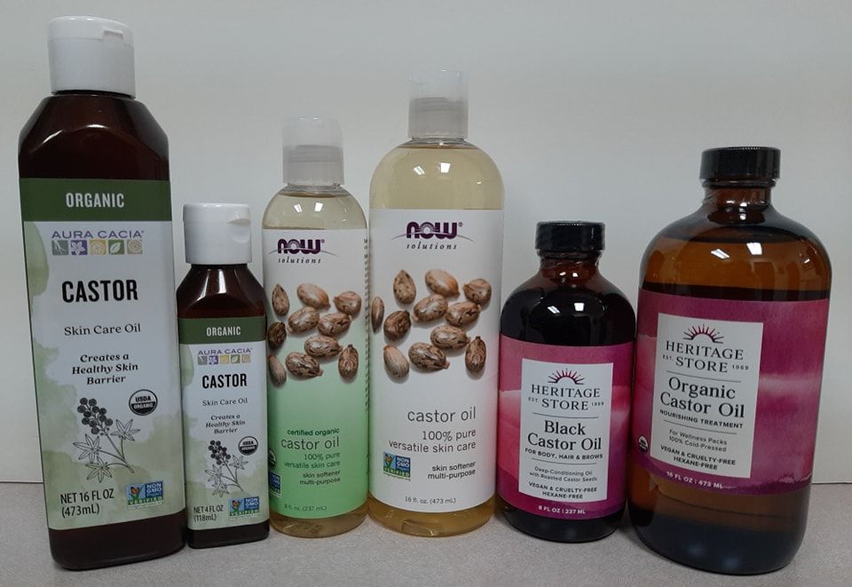 Six bottles of various brands of castor oil lined up against a white background.