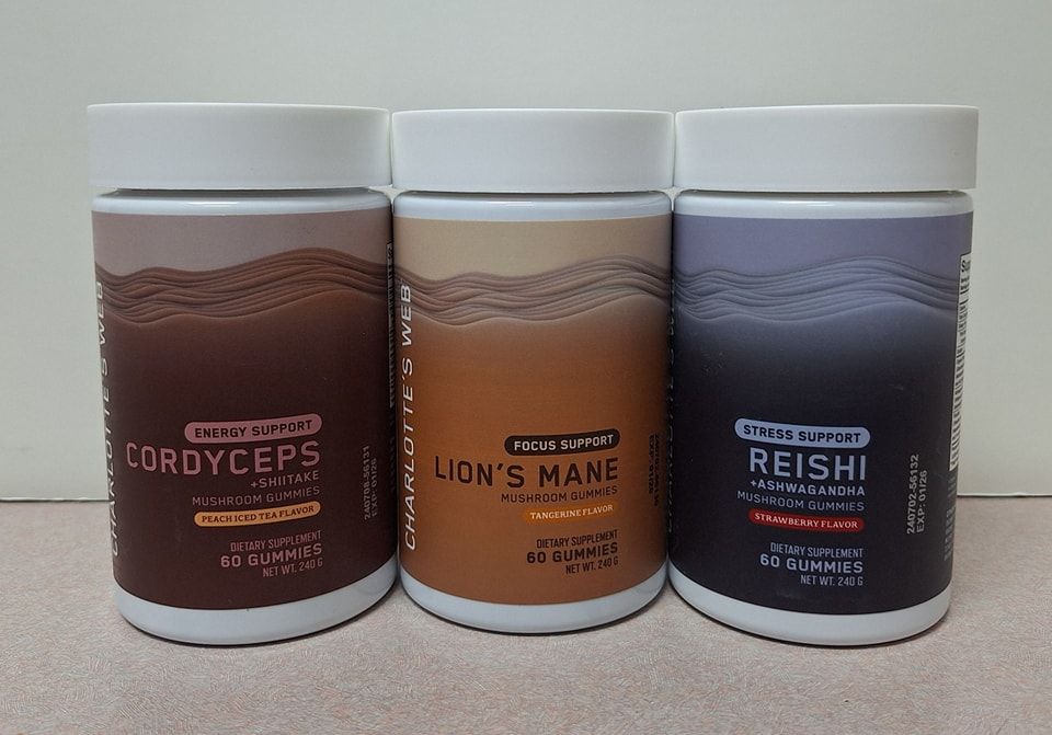 Three bottles of Charlotte’s Web mushroom gummies—Cordyceps, Lion’s Mane, and Reishi—aligned on a light-colored surface.