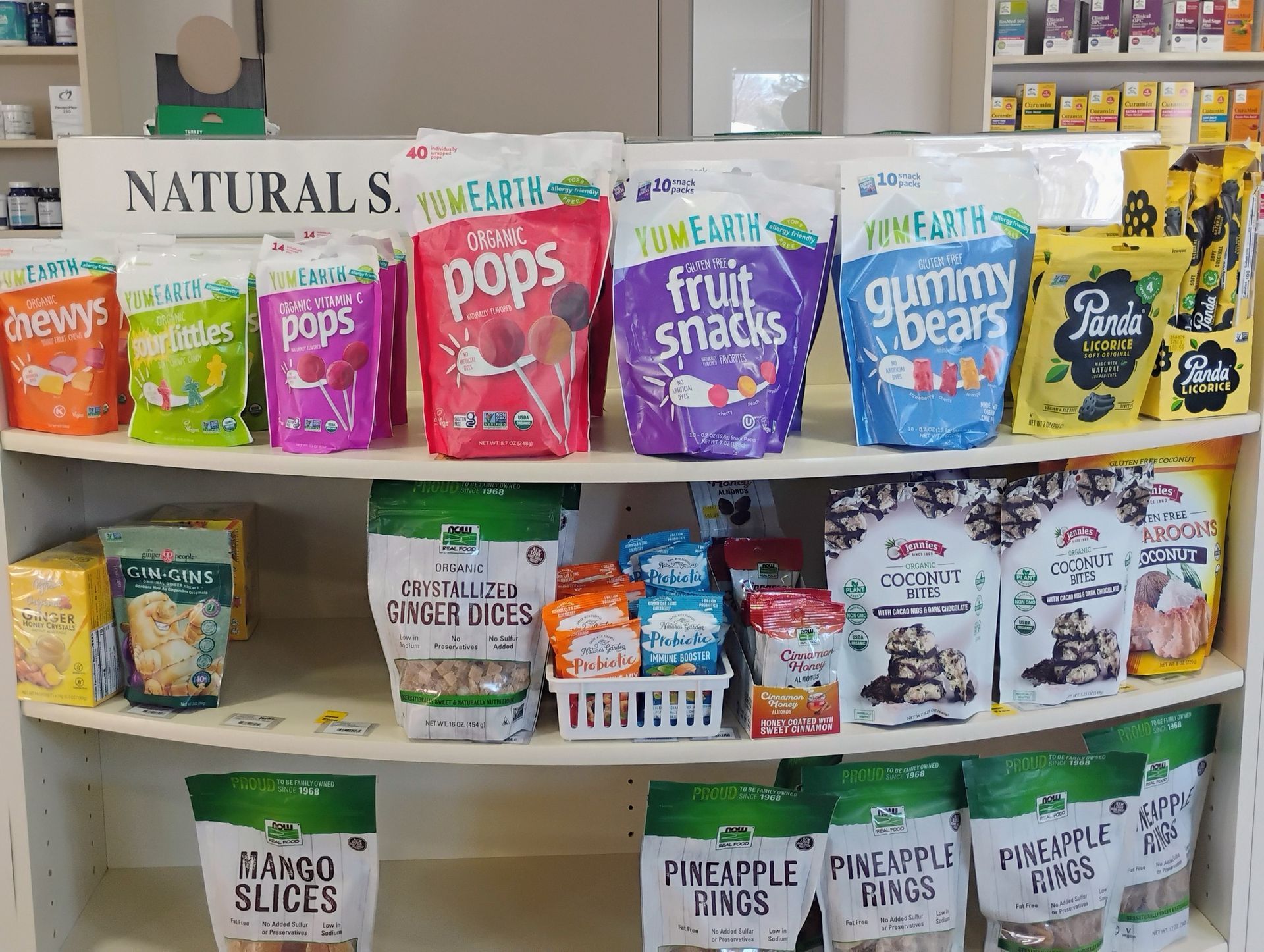 Shelf display of various packaged snacks: pops, fruit snacks, gummy bears, and more.