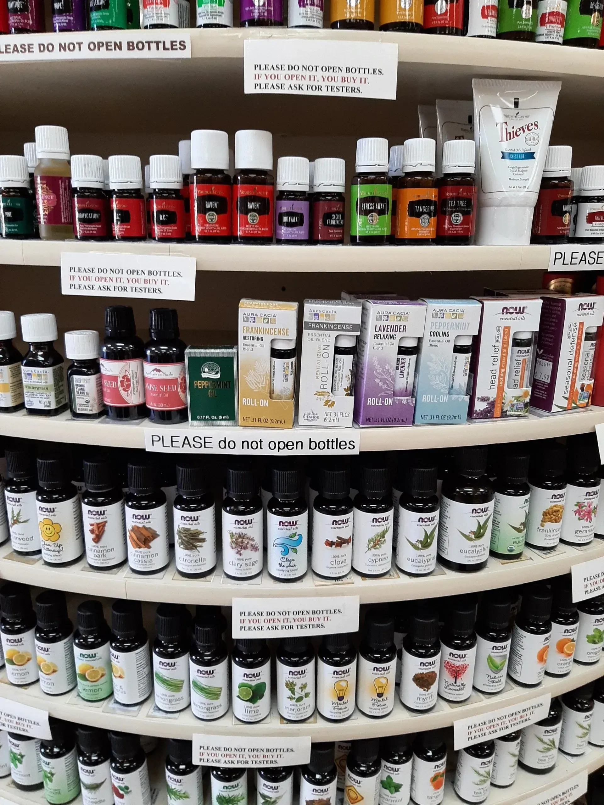 A multi-level retail display rack filled with various small essential oil bottles and boxes.