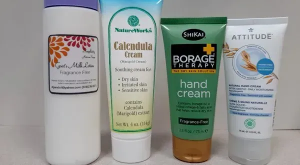 Four tubes of hand and body cream from brands including NatureWorks, ShiKai, and Attitude arranged on a white surface.