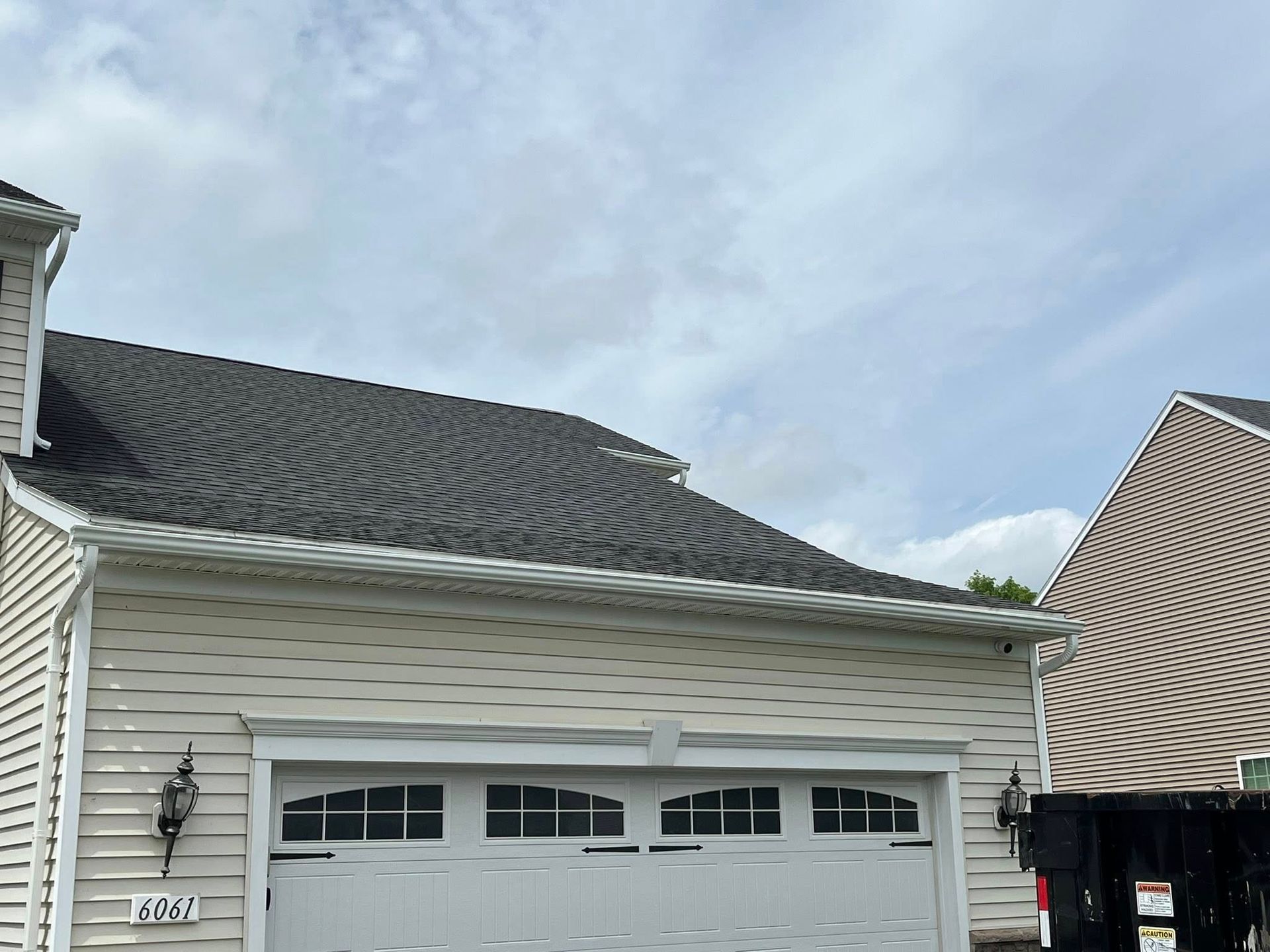 Gutters installed above a garage on a pale yellow house