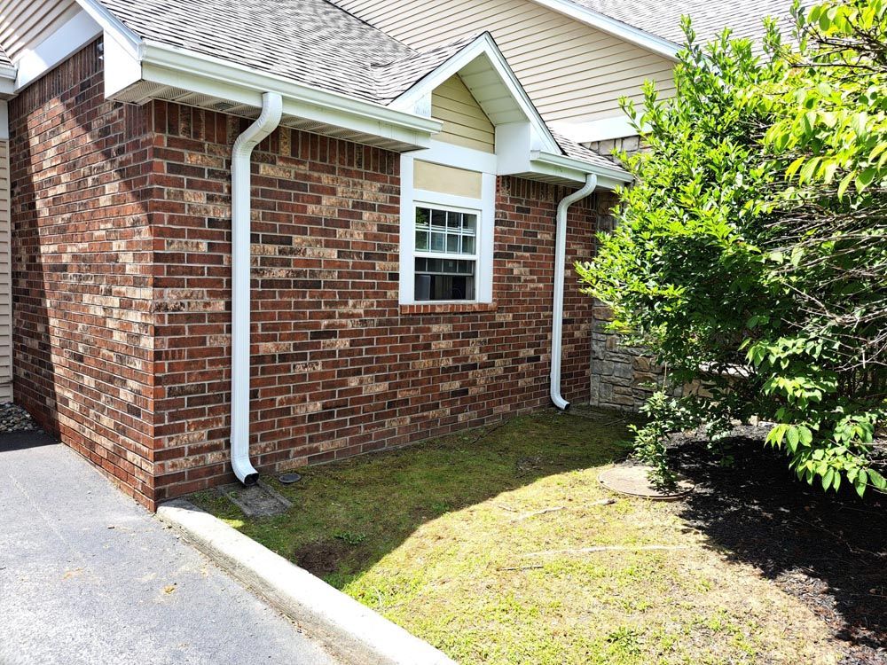 Two downspouts on a brick house from a gutter installation in Rochester, NY
