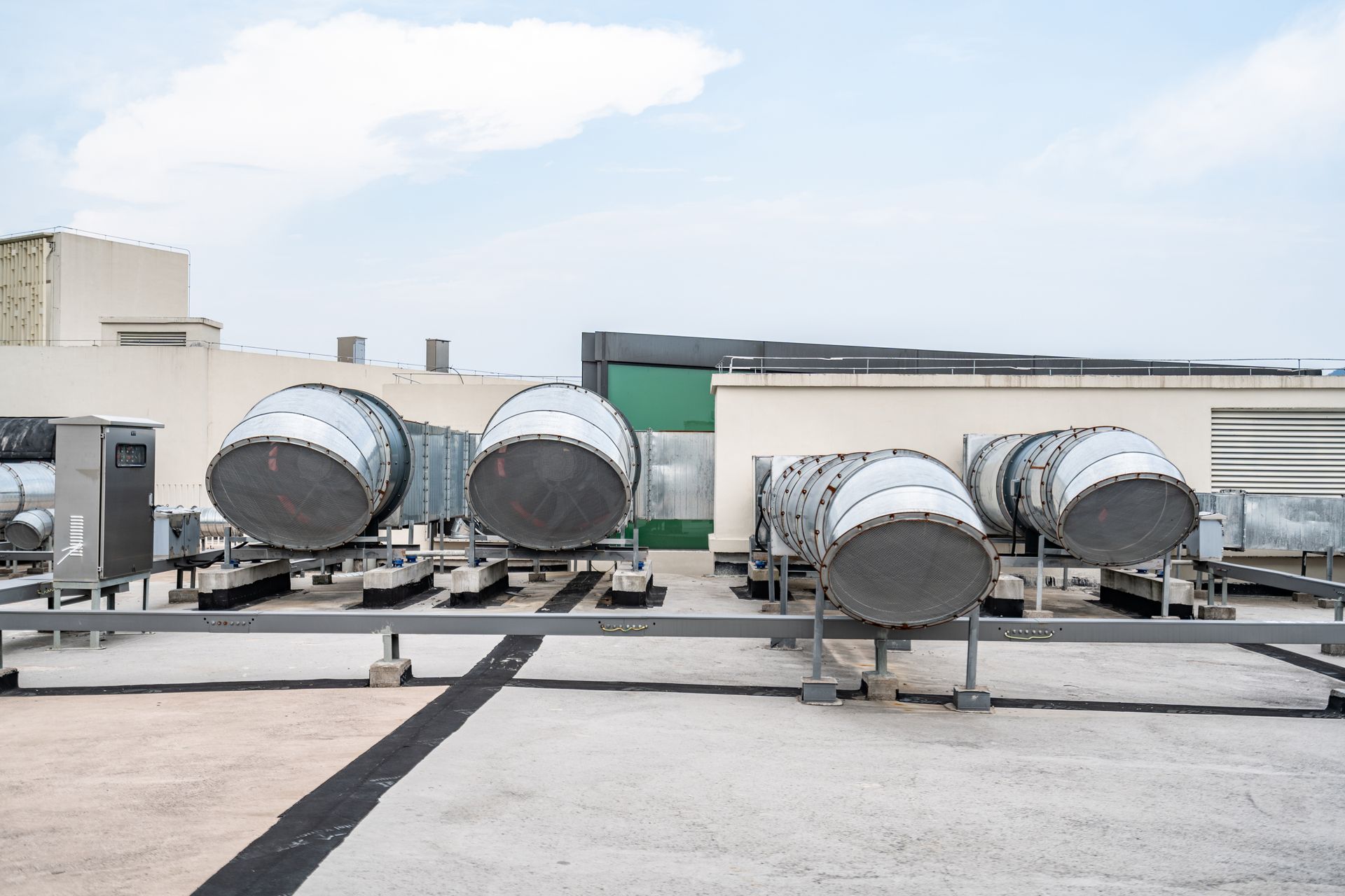 Row of air conditioning units on a rooftop, with white units against a blue sky. Row of air conditioning units on a rooftop, with white units against a blue sky.