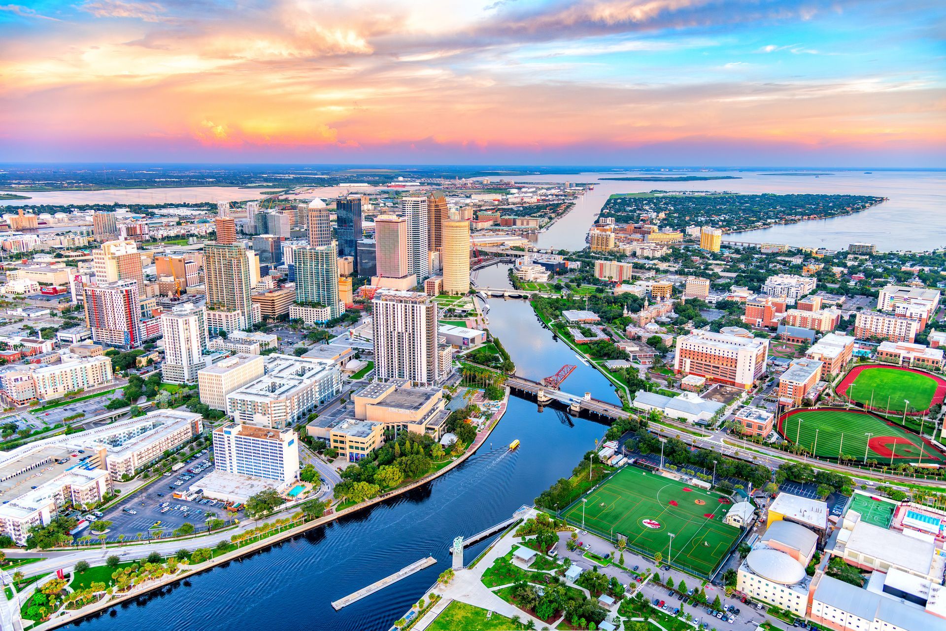 Aerial view of Tampa, Florida, cityscape with river, buildings, and a colorful sunset. Aerial view of Tampa, Florida, cityscape with river, buildings, and a colorful sunset.