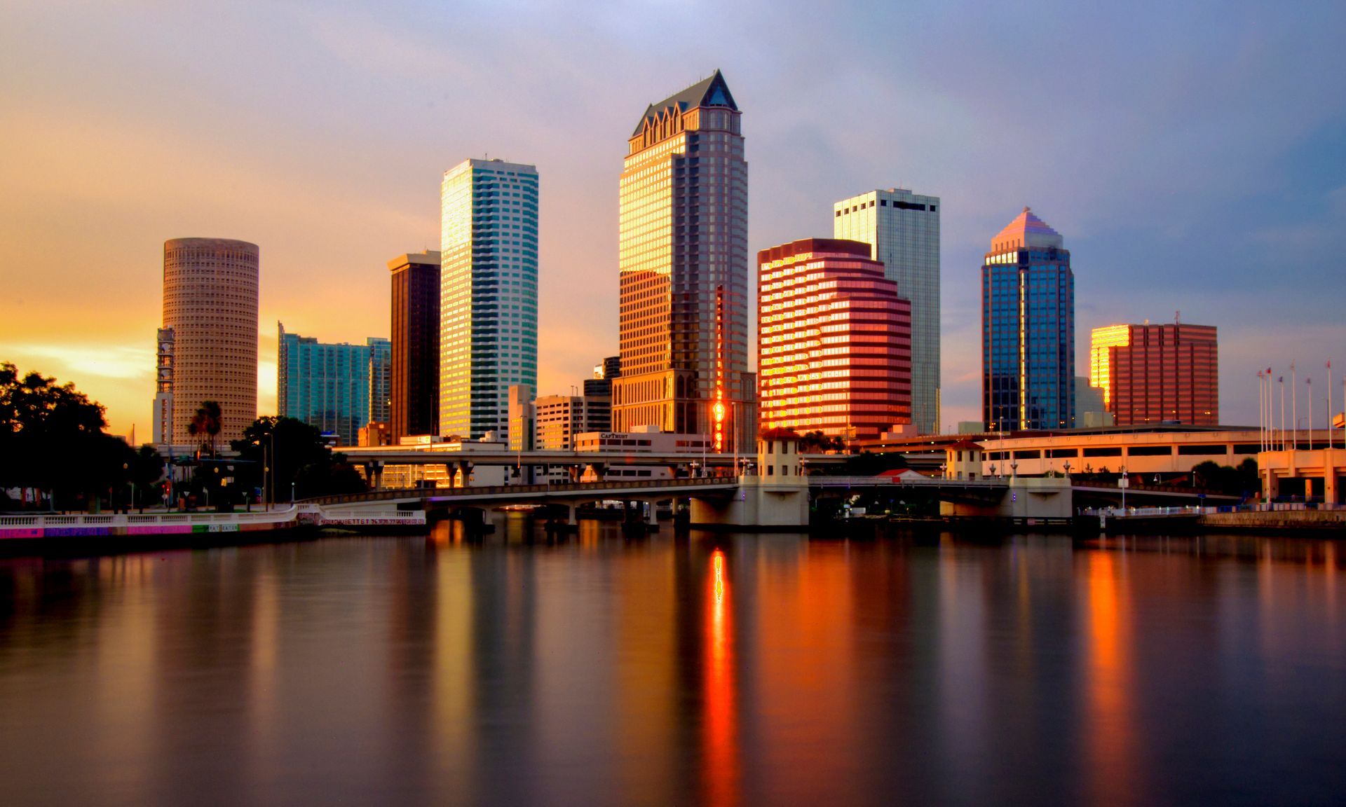 Skyline of Tampa, Florida, at sunset, with buildings reflecting warm light on the water. Skyline of Tampa, Florida, at sunset, with buildings reflecting warm light on the water.