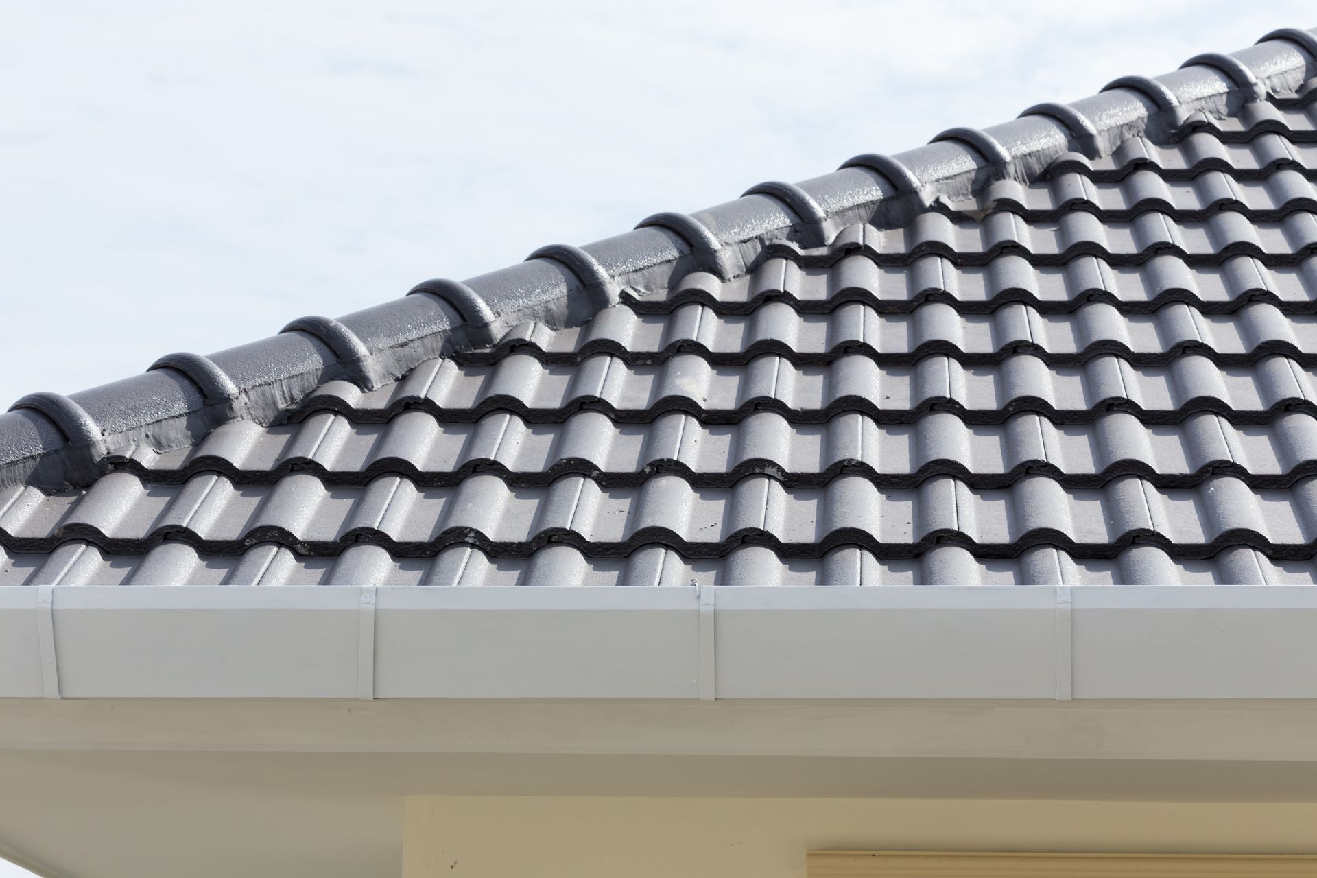 Dark gray tile roof with white trim and a blue sky.