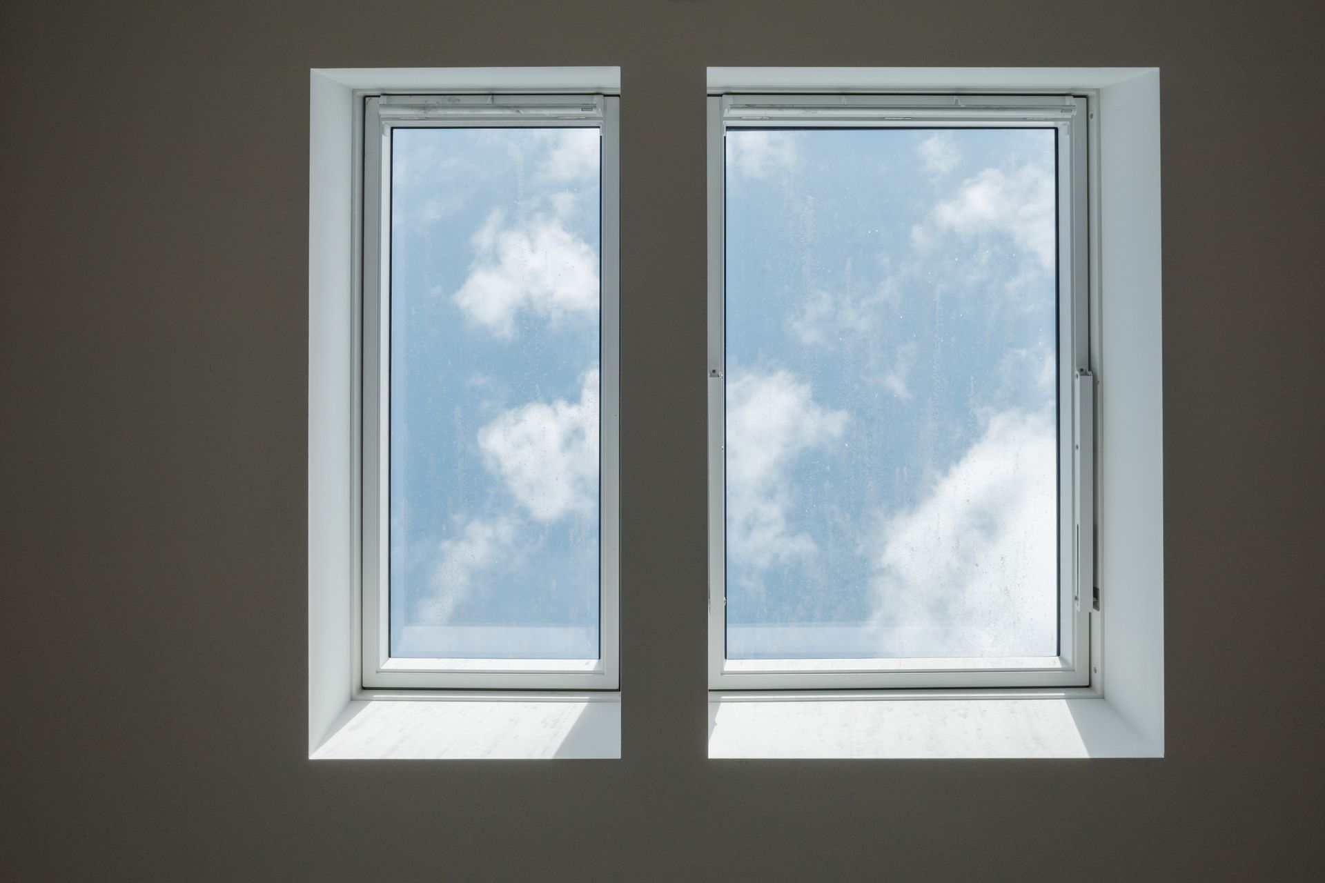 Two rectangular windows with a view of a blue sky and white clouds.