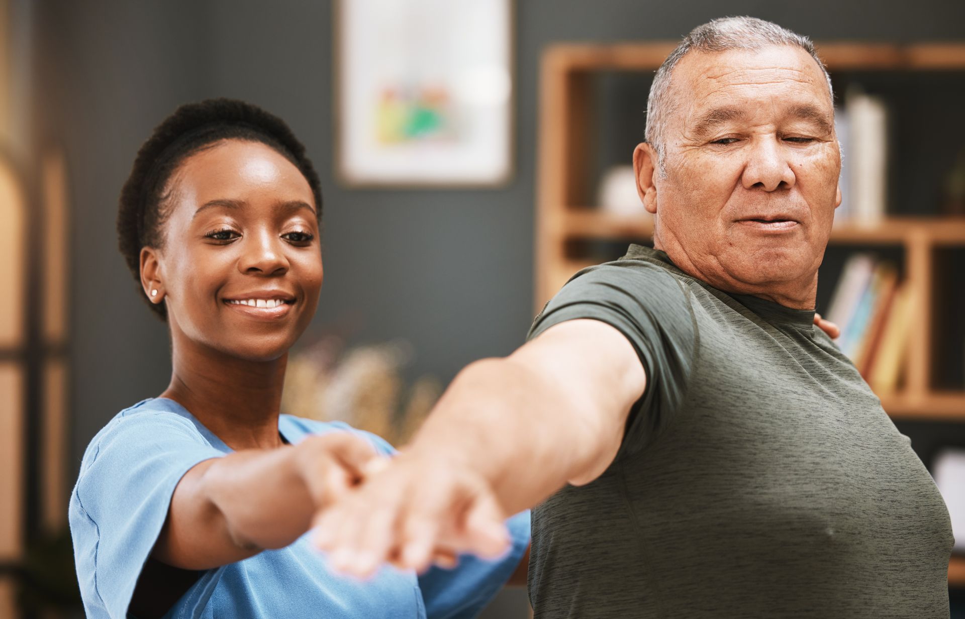 A nurse is helping an elderly man stretch his arms.