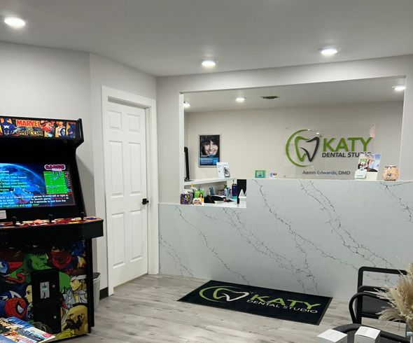 A dental office with a arcade machine and a reception desk.